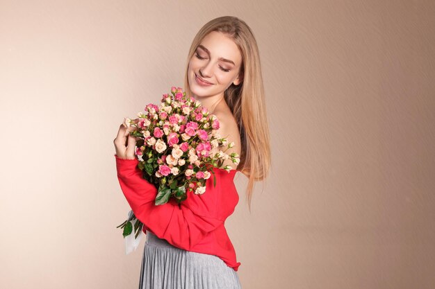 Belle jeune femme avec bouquet de roses sur fond de couleur