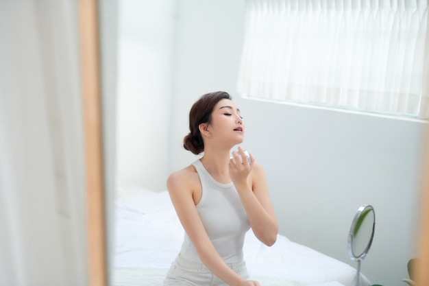 Belle jeune femme avec une bouteille de parfum sur fond blanc