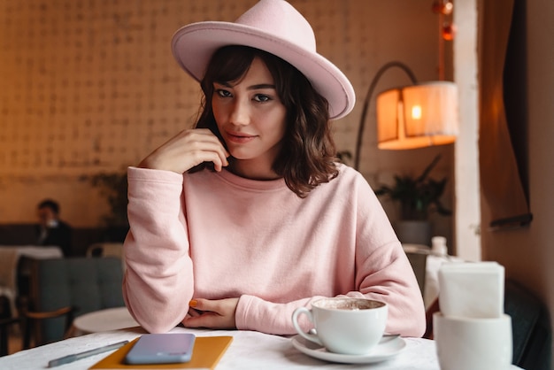 une belle jeune femme brune assez magnifique à l'intérieur s'asseoir au café.