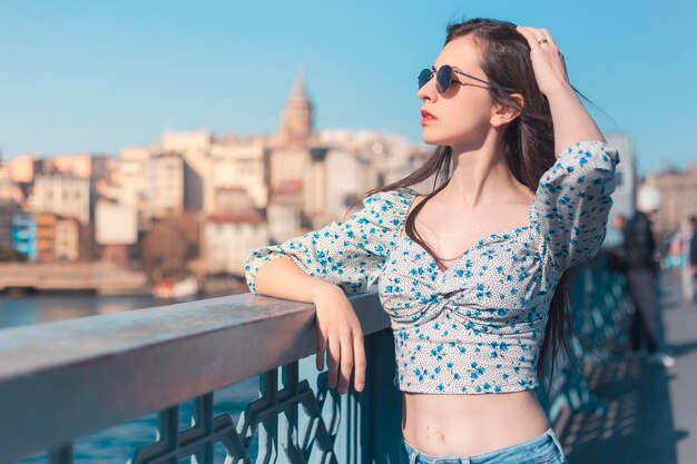 Belle jeune femme brune aux cheveux longs regardant à l'horizon avec ses lunettes de soleil copie espace