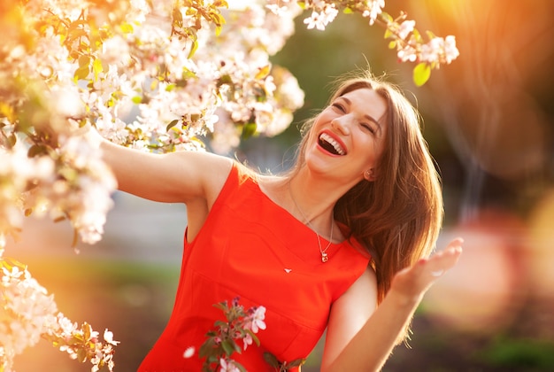 Photo belle jeune femme brune debout près de l'arbre en fleurs