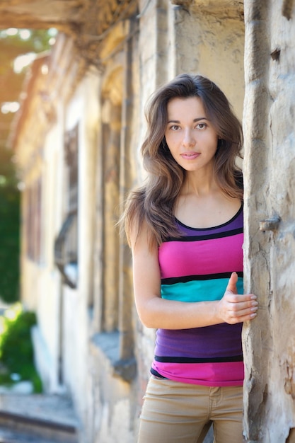 Belle jeune femme brune debout près du vieux mur de pierre
