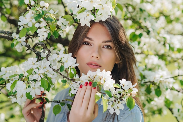 Belle jeune femme brune debout près de pommier en fleurs