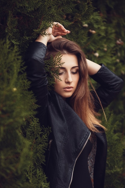 Belle jeune femme brune souriante avec des fleurs dans le parc automne