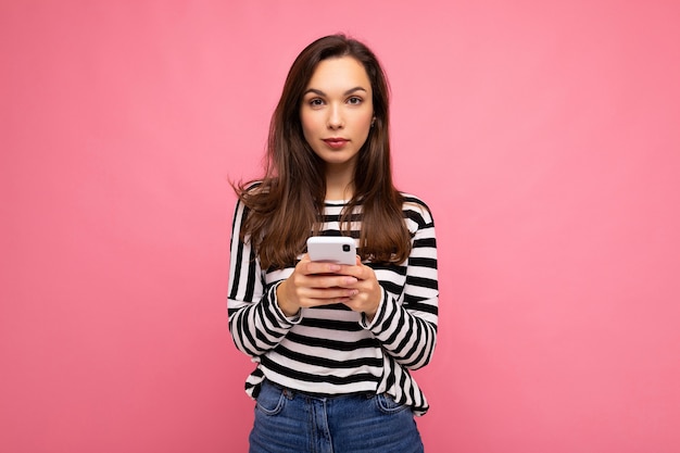 Belle jeune femme brune utilisant un téléphone portable communiquant par SMS portant un pull