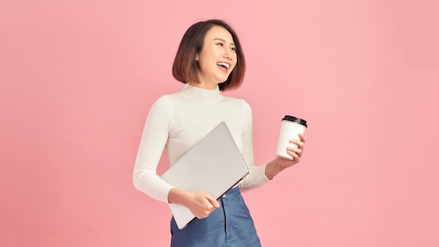 Belle jeune femme buvant du café tenant le presse-papiers isolé sur fond rose