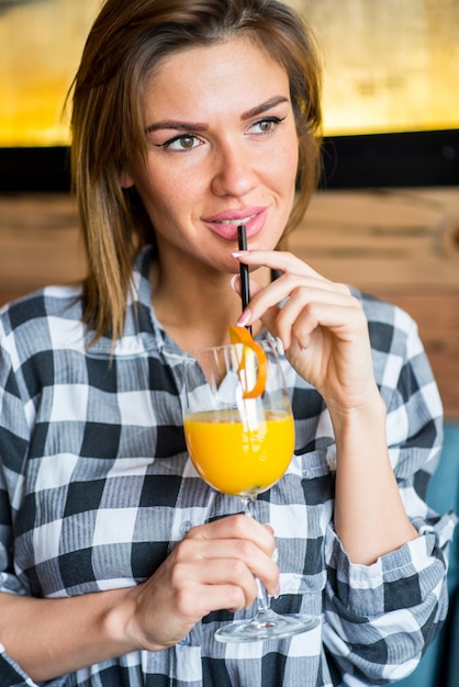 Belle jeune femme buvant du jus d'orange