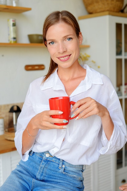 belle jeune femme buvant du thé dans la cuisine avec du citron