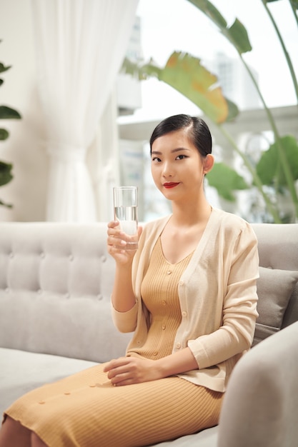 Belle jeune femme buvant de l'eau à la maison