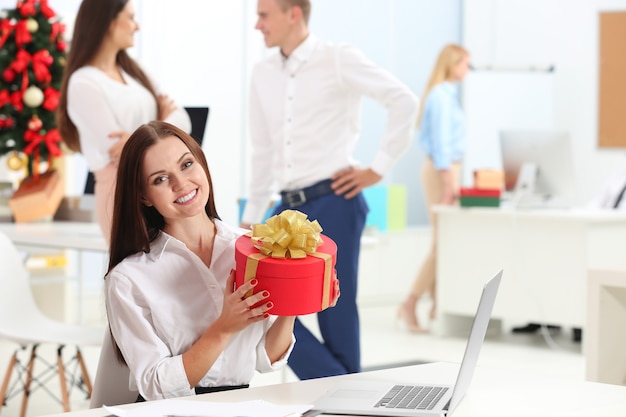 Belle jeune femme avec cadeau de Noël au bureau