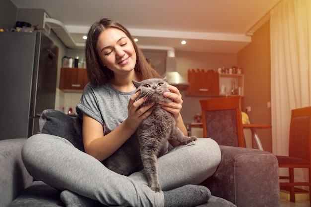 belle jeune femme caressant un drôle de chat britannique