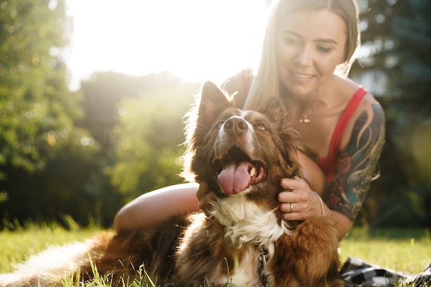 Belle jeune femme caressant son chien mignon dans le parc