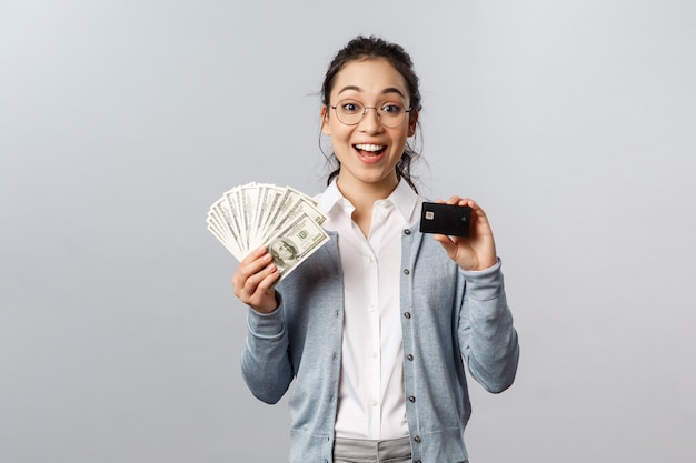 Belle jeune femme avec carte de crédit noire et argent comptant