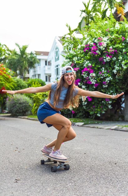 Une belle jeune femme avec une casquette qui fait du skateboard et rit.