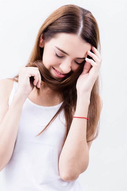 Belle jeune femme caucasienne heureuse, jouant avec les cheveux longs en bonne santé