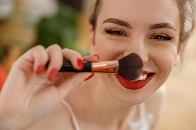 Belle jeune femme caucasienne heureuse à la maison confortable avec des cosmétiques au matin ensoleillé