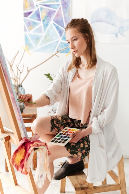 Belle jeune femme caucasienne peintre à l'espace de travail