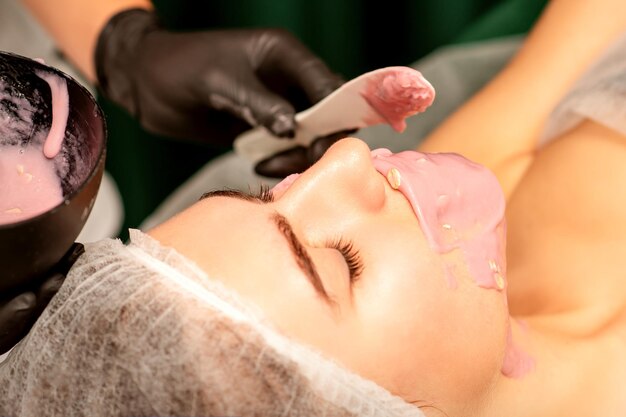 Photo belle jeune femme caucasienne recevant un masque alginique au visage dans un salon de beauté traitement de la peau du visage