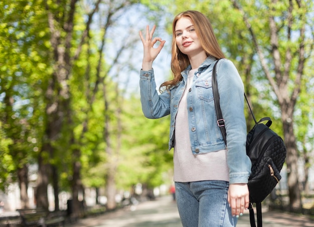 Belle jeune femme caucasienne en vêtements en denim montrant un geste correct dans la ville