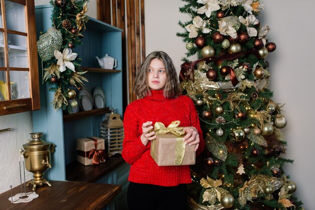 Belle jeune femme célébrant Noël à la maison, s'amusant en ouvrant des cadeaux