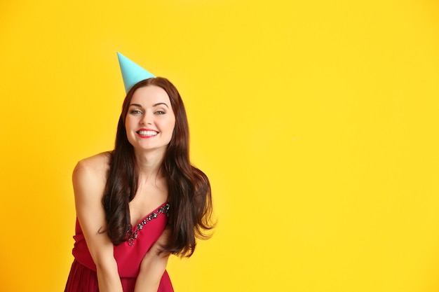 Belle jeune femme en chapeau de fête sur fond jaune