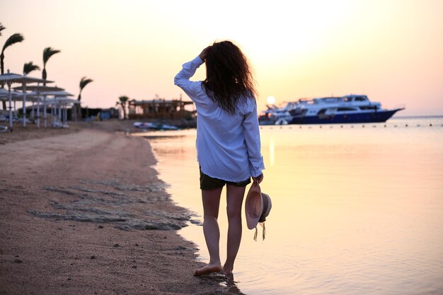 belle jeune femme en chapeau et jeans debout au bord de la mer