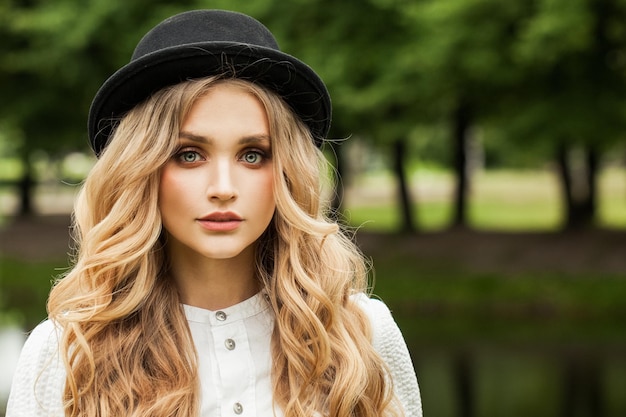 Une belle jeune femme avec un chapeau noir à l'extérieur