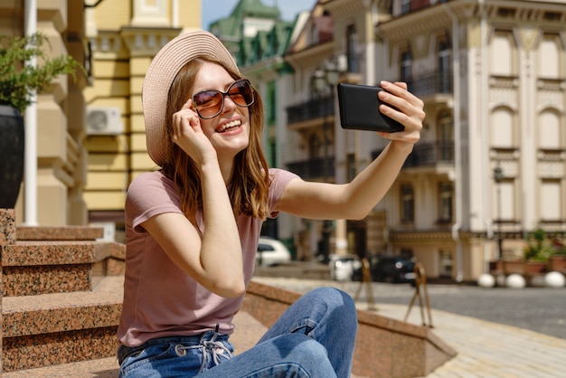 Belle jeune femme avec un chapeau prenant un selfie