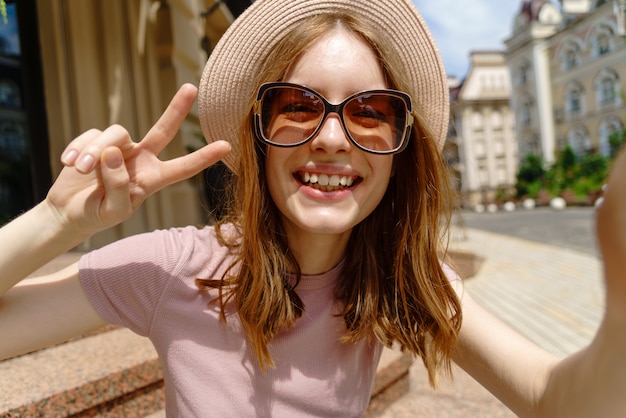 Belle jeune femme avec un chapeau prenant un selfie