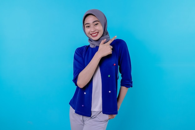 Belle jeune femme charismatique portant le hijab pointant isolé sur fond bleu clair