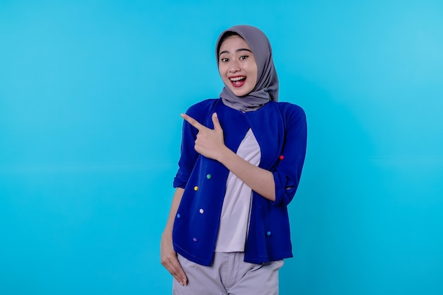 Belle jeune femme charismatique portant le hijab pointant isolé sur fond bleu clair