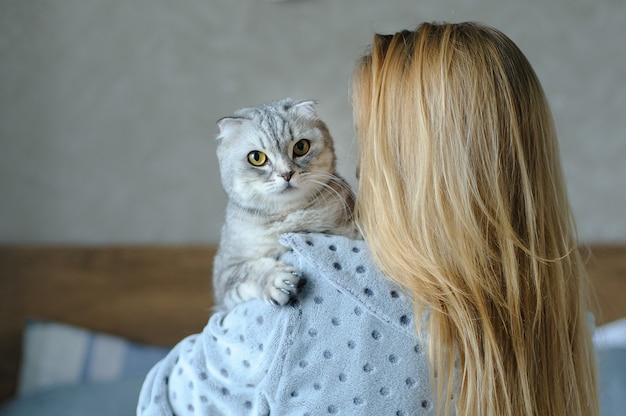 Belle jeune femme avec chat mignon sur un lit