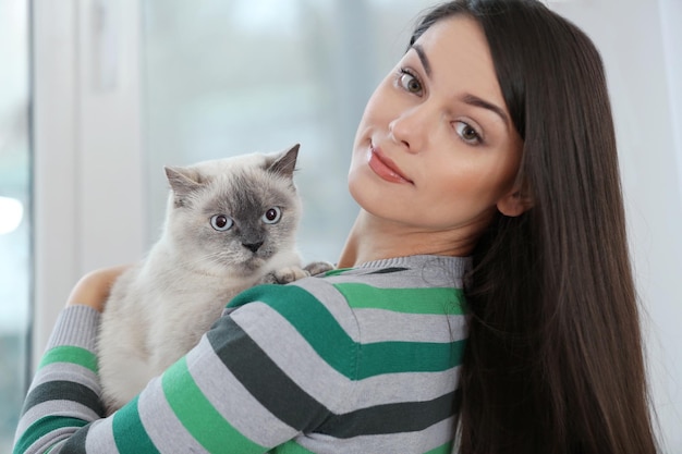 Belle jeune femme avec chat mignon à la maison