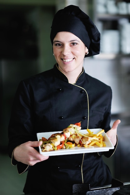 belle jeune femme chef prépare et décore des plats savoureux dans la cuisine