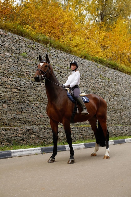 Belle jeune femme à cheval en plein air Concept de soins aux animaux Repos rural et loisirs Idée de tourisme vert Jeune femme européenne portant casque et uniforme