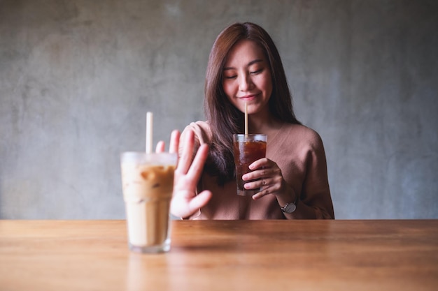 Une belle jeune femme choisissant de boire du café noir et faisant signe de la main pour refuser le café au lait sucré