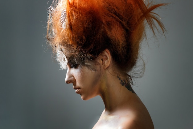 Belle jeune femme avec une coiffure avant-gardiste compliquée. Tonifiant, photo d&#39;art.