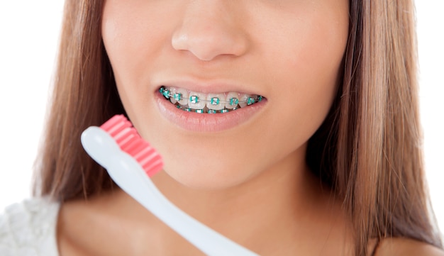 Belle jeune femme avec des crochets en train de nettoyer ses dents