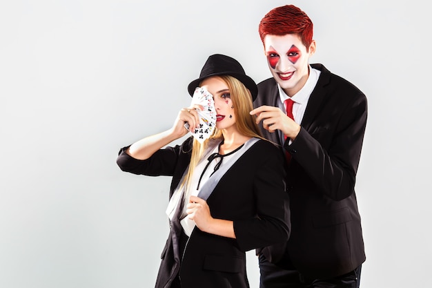 Une belle jeune femme croupier et garçon avec un joker maquillage artistique. Concept de jeu et de casino. Tourné en studio. Fond blanc .