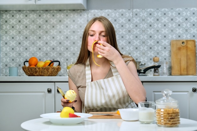 Belle jeune femme cuisine de délicieux aliments diététiques sains à la maison. Sur la table sont des fruits, des céréales, des produits laitiers. Beauté, jeunesse, mode de vie sain et alimentation saine