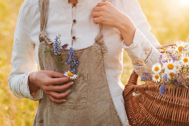 Belle jeune femme dans un champ de fleurs jouit de l'arôme et de la vue des marguerites des champs