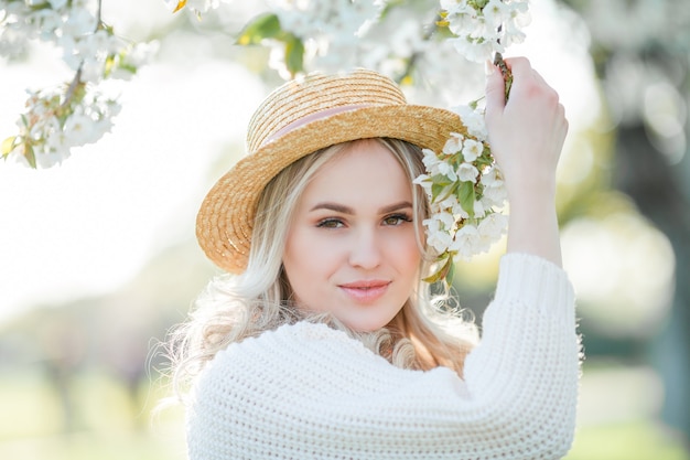 Belle jeune femme dans un chapeau en osier repose sur un pique-nique dans un jardin fleuri