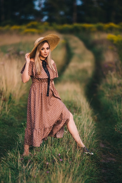 Belle jeune femme dans un chapeau et une robe se promène dans la nature en automne.