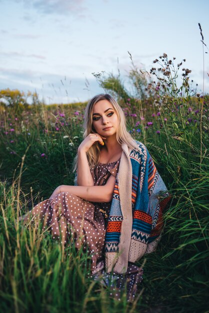 Belle jeune femme dans un chapeau et une robe se promène dans la nature en automne.