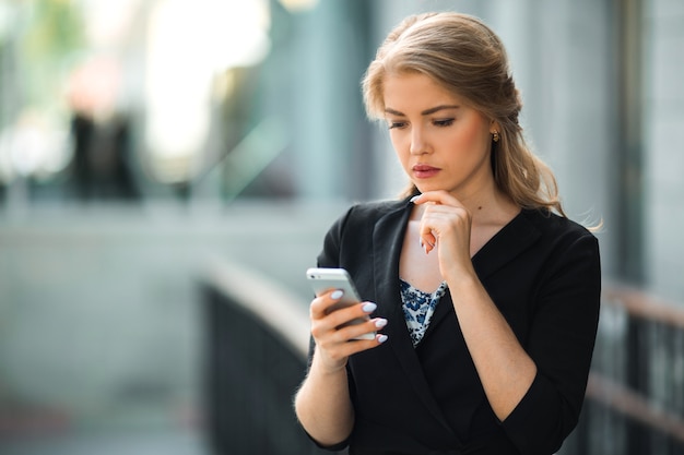 belle jeune femme dans un costume noir avec un téléphone dans ses mains