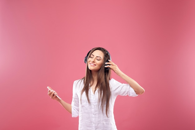 Belle jeune femme dans des écouteurs sans fil écoutant de la musique à l'aide d'un téléphone portable