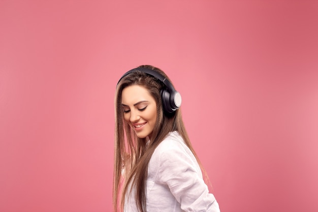 Belle jeune femme dans des écouteurs sans fil, écouter de la musique et danser