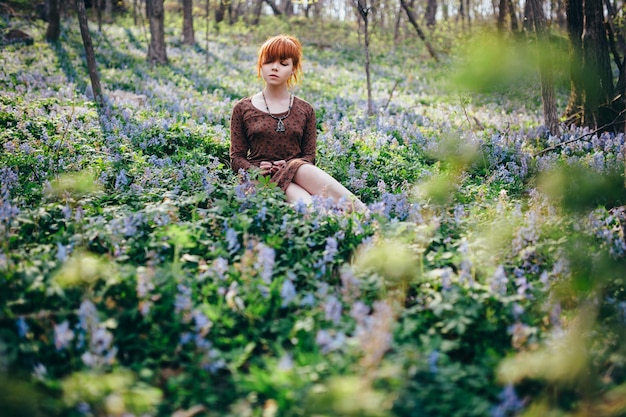 Belle jeune femme dans la forêt avec des fleurs de printemps