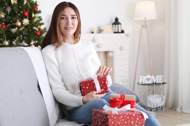 Belle jeune femme dans un intérieur de Noël avec des cadeaux pour texte