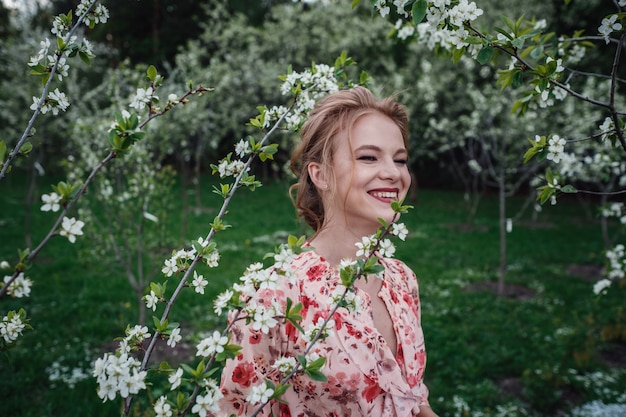 Belle jeune femme dans le jardin de cerisiers en fleurs.